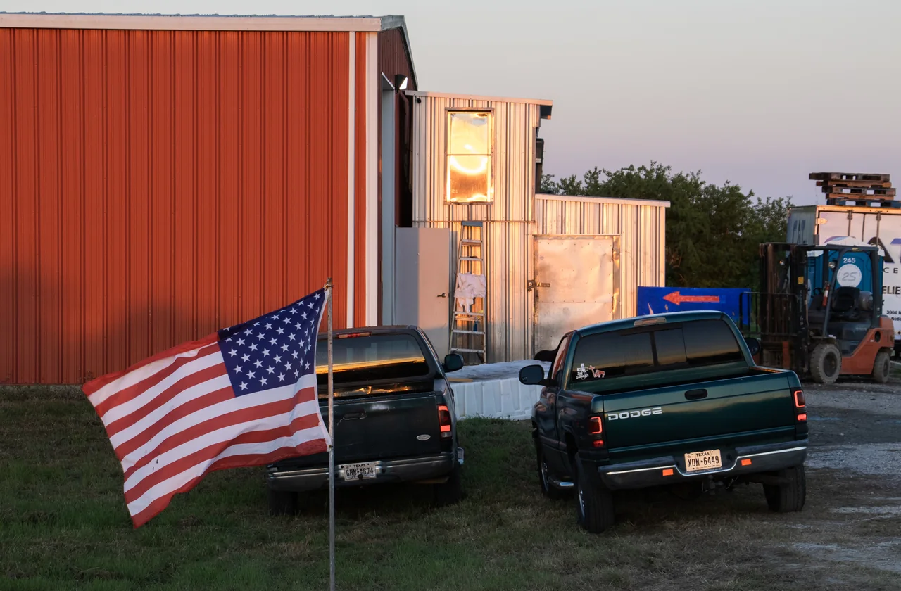 An American flag in front of the red Gator House barn in the evening light