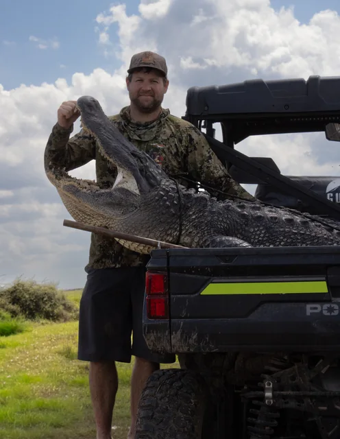 Customer in camouflage posing with an alligator on a utility vehicle