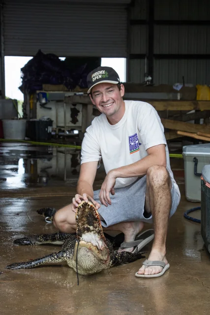 Customer in a white shirt posing with his alligator inside the shop
