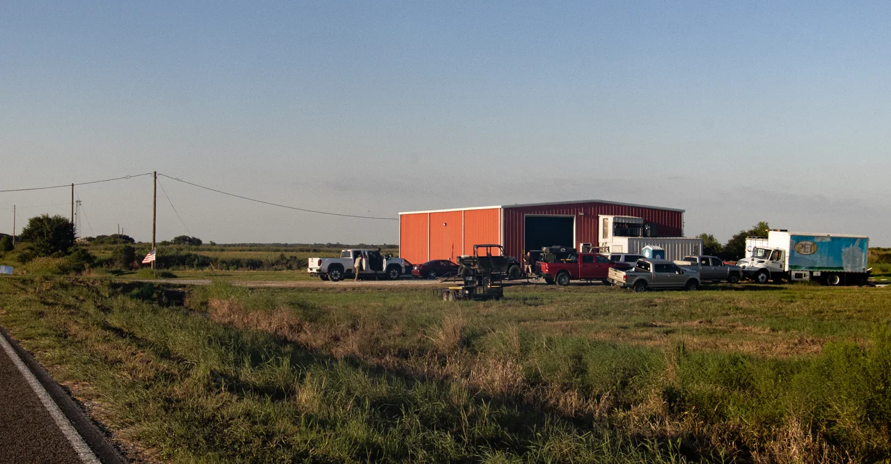 The red Gator House barn and vehicles, seen from the roadside in Winnie, Texas