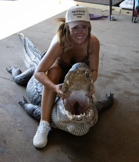 Customer in a cap posing with an alligator inside the barn