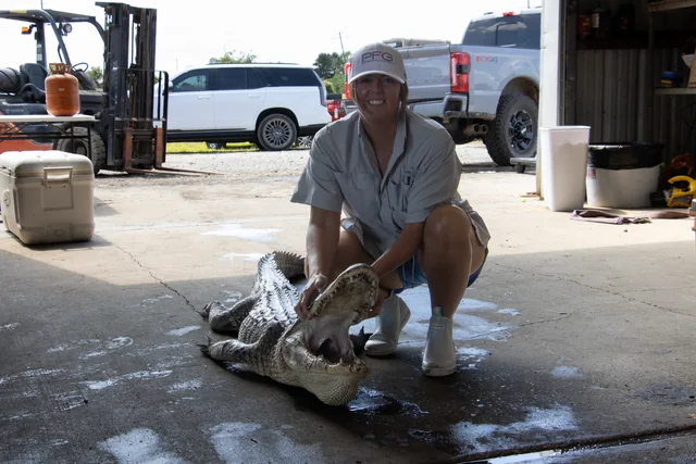 Customer in boots posing with an alligator at the shop entrance