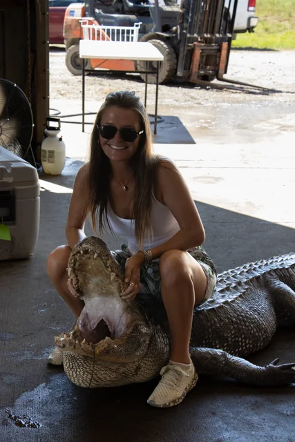 Customer in sunglasses posing with an alligator inside the barn