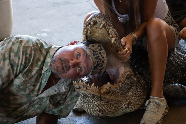 Customer posing beside an alligator with its jaw open