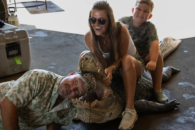 Three visitors posing with an alligator inside the shop